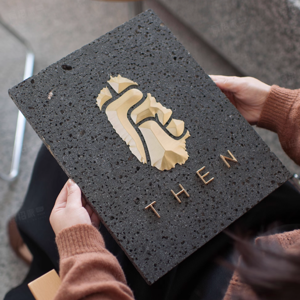 Person holding a dark textured book with 'THEN' embossed on it.