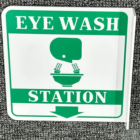 Safety sign with eye wash station instructions on a textured surface