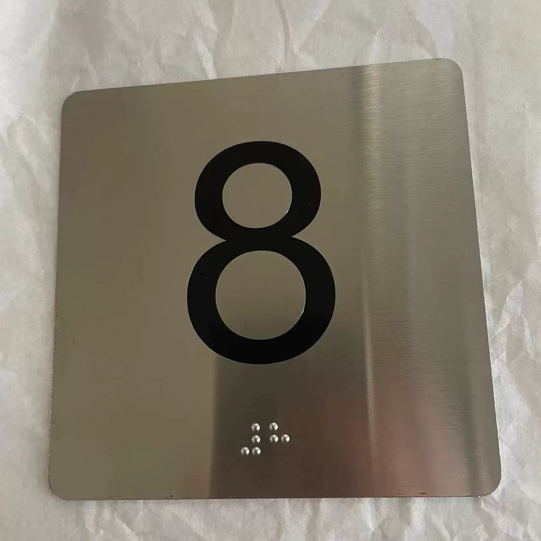 Metallic sign with the number '8' on a textured white background